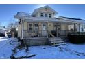 Yellow bungalow with porch and snowy yard at 1709 W 11Th St, Muncie, IN 47302