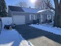 Gray ranch house with a snow-covered driveway and attached garage at 1801 E 23Rd St, Muncie, IN 47302