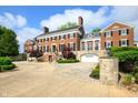 Expansive driveway leading to a grand red brick home with meticulously maintained landscaping and attached garages at 4601 N Legacy Dr, Muncie, IN 47304