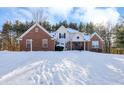 Brick and siding two-story home nestled in a snowy landscape at 125 Chalet Dr, Mooresville, IN 46158