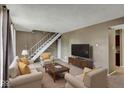 Bright living room features carpeted floors, seating, white stairs, and a modern entertainment center at 4814 Oakwood Trl, Indianapolis, IN 46268
