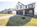 Exterior of home with dark trim, showcasing the garage, front yard, and proximity to neighborhood houses at 801 Blaine Dr, Whiteland, IN 46184