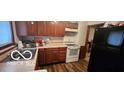 Efficient kitchen with wood cabinets, white appliances, and vinyl flooring at 1313 S Riley Ave, Indianapolis, IN 46203