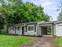 Quaint single-story home featuring gray siding, black shutters, a lush green lawn and an attached carport at 5807 Westhaven Dr, Indianapolis, IN 46254