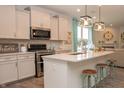 Modern kitchen with white cabinets, quartz countertops, and a large island with seating at 17242 Cole Evans Dr, Noblesville, IN 46060