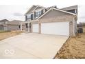 Long driveway and attached two-car garage of this charming home featuring a brick facade and gray siding at 6039 Granby Dr, Whitestown, IN 46075