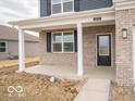 Charming front porch featuring white columns, brick facade, a black door, and a well-manicured lawn at 6039 Granby Dr, Whitestown, IN 46075