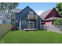 A spacious backyard with lush grass, a wooden deck, and a second-story balcony at 730 Sanders St, Indianapolis, IN 46203