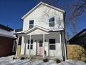 Two-story white house with pink door, covered porch, and snow-covered yard at 1306 E Minnesota St, Indianapolis, IN 46203