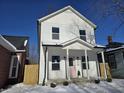 Two-story white house with pink door, covered porch, and snow-covered yard at 1306 E Minnesota St, Indianapolis, IN 46203