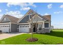 Charming home featuring a lush lawn, two-car garage, and inviting front entrance with stone accents at 16673 Cattle Hollow Ln, Noblesville, IN 46060