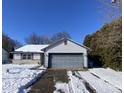 Ranch home with gray garage door and stone accents. Snow on the ground at 3332 Lauren Dr, Indianapolis, IN 46235