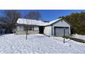 Ranch home with gray garage door and stone accents. Snow covered yard at 3332 Lauren Dr, Indianapolis, IN 46235