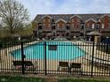 Community pool with lounge chairs and umbrellas surrounded by manicured landscaping and wrought iron fence at 6595 Reserve Dr, Indianapolis, IN 46220