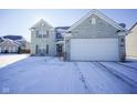 Two-story house with stone exterior, snowy yard, and attached garage at 10963 Field Crescent Cir, Noblesville, IN 46060