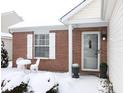 Brick front entry with white door and storm door, and snowy landscaping at 12306 Split Granite Dr, Fishers, IN 46037