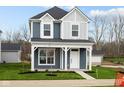 Charming two-story home featuring a covered porch, blue siding, and a well-maintained lawn at 1705 Real St, Indianapolis, IN 46240