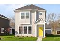 Charming two-story home with light gray siding, white trim, bright yellow door and manicured lawn at 1709 Real St, Indianapolis, IN 46240
