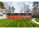 Charming red home exterior with a well-manicured lawn and a neat sidewalk leading to the front at 2894 W Grove Dr, Greenfield, IN 46140