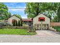 View of home featuring two-car garage, red awnings, and stone retaining wall at 6072 Meridian St W Dr, Indianapolis, IN 46208