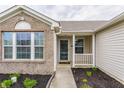 Covered front porch with white railings and brick facade in a single Gathering home at 1681 Copeland Farms Dr, Greenfield, IN 46140