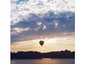 A hot air balloon floats above the water during sunset, creating a picturesque and serene scene at 3150 Beach Blvd, Cicero, IN 46034