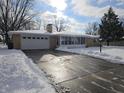 Ranch home with a snow-covered driveway, attached garage, and sunroom at 515 Wedgewood Dr, Anderson, IN 46013