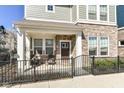 Charming front porch with stylish chairs, and a stone front, enclosed by a black metal fence at 9217 Hawley Dr, Indianapolis, IN 46216
