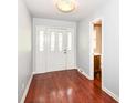 Bright foyer with dark wood floors, white paneled front door, and access to a nearby powder room at 475 Golf Ln, Indianapolis, IN 46260