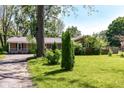 A single-story brick home with lush green lawn and mature trees under a blue sky, creating a serene setting at 475 Golf Ln, Indianapolis, IN 46260