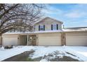 Charming townhouse with a two-car garage, brick accents, and snow-covered landscaping at 7218 Forrester Ln, Indianapolis, IN 46217