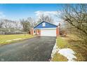 View of a brick home with an attached garage and a long black driveway at 7817 Dartmouth Rd, Indianapolis, IN 46260