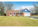 Brick ranch home with a blue accent, attached garage, and a well-maintained lawn at 7817 Dartmouth Rd, Indianapolis, IN 46260