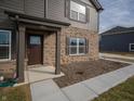 Welcoming front entrance featuring a brown door, brick columns, and a well-maintained sidewalk at 7872 Magnolia St, New Palestine, IN 46163