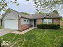 Ranch home features a brick facade, attached garage, and well-manicured lawn at 825 Queensgate Dr, Greenwood, IN 46143