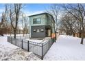 Modern teal and gray house with black fence and snowy yard; inviting curb appeal at 1656 Roosevelt Ave, Indianapolis, IN 46218