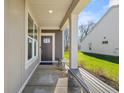 Inviting covered front porch with gray door, side panel, and sitting bench provides curb appeal at 19357 Sumrall Pl, Westfield, IN 46074