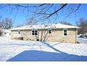 Tan exterior rear of ranch home with snowy backyard and trees at 67 W Brookville Rd, Fountaintown, IN 46130
