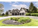 Spacious three-car garage with a circular driveway and landscaped flower bed at 14990 E 104Th St, Fishers, IN 46040