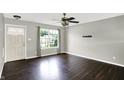 Bright living room features a large window with backyard views and dark hardwood floors, and modern ceiling fan at 5327 Milhouse Rd, Indianapolis, IN 46221