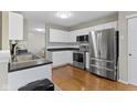 Bright kitchen boasts stainless steel appliances, white cabinetry, and wood-look flooring at 13494 Forum Meadows Dr, Carmel, IN 46033