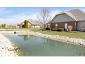 Backyard featuring a scenic pond with landscaped surroundings and well-maintained lawn at 2811 Grandview Ln, Greenwood, IN 46143