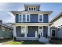 Charming blue two-story home with white trim, inviting front porch and landscaped yard at 404 N Gray St, Indianapolis, IN 46201