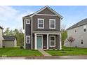 Charming two-story home with gray siding, white trim, a quaint porch and lush green lawn at 1713 Real St, Indianapolis, IN 46240