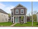 Charming two-story home with gray siding, white trim, a quaint porch and lush green lawn at 1713 Real St, Indianapolis, IN 46240