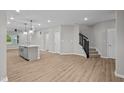 Open-concept living space features wood floors, neutral paint, a kitchen island, and a modern staircase at 1721 Real St, Indianapolis, IN 46240