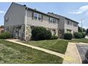 Townhome exterior with stone accents, tidy lawn, and concrete walkway to front door at 2634 Country Estates Dr # 17, Indianapolis, IN 46227