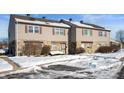Tan siding duplex with stone accents, snowy front yard, and walkways at 2634 Country Estates Dr # 17, Indianapolis, IN 46227