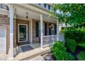 Inviting front porch with white railing, brick accents, and blooming hanging plants at 3460 Limelight Ln, Whitestown, IN 46075