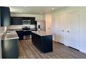 Features black cabinetry, an island, stainless steel appliances, and wood-look flooring at 371 Traditions Pass, Greenwood, IN 46143